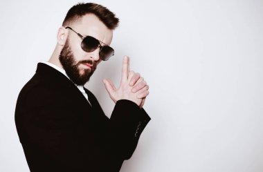 Zarif siyah bir takım elbise ve siyah gözlük bağı poz içinde ayakta acımasız yakışıklı, sakallı adam.