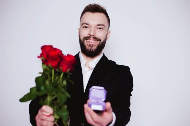 Benim karım olur. Kırmızı gül ve alyans beyaz zemin üzerinde bir kutu içinde zarif güzel gülümseyen adam.