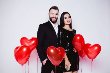 Bir kalp şeklinde kırmızı balon güzel genç çift bir arka plan siyah şık kostümleri aşık. Sevgililer günü