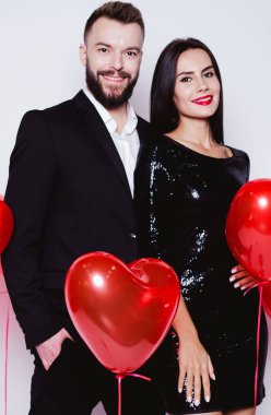 Bir kalp şeklinde kırmızı balon güzel genç çift bir arka plan siyah şık kostümleri aşık. Sevgililer günü