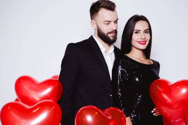 Bir kalp şeklinde kırmızı balon güzel genç çift bir arka plan siyah şık kostümleri aşık. Sevgililer günü