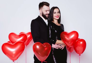 Bir kalp şeklinde kırmızı balon güzel genç çift bir arka plan siyah şık kostümleri aşık. Sevgililer günü