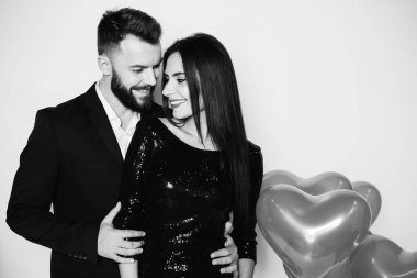 Bir kalp şeklinde kırmızı balon güzel genç çift bir arka plan siyah şık kostümleri aşık. Sevgililer günü