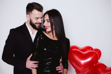 Bir kalp şeklinde kırmızı balon güzel genç çift bir arka plan siyah şık kostümleri aşık. Sevgililer günü
