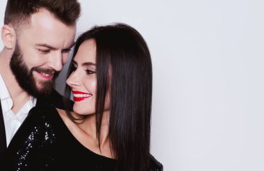 Bir güzel gülümseyen portresi yakın çift kucaklayan izole beyaz bir arka plan üzerinde siyah gece elbisesi içinde sevgi dolu.