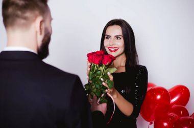 Aşık tatil tebrik ediyorum. Çiçek ve hediye için mutlu kadını Sevgililer Günü'nde veren gülümseyen adam.
