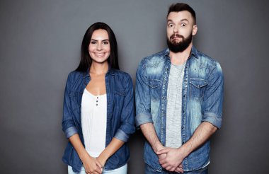 Güzel ve mutlu genç çift aşk veya aile eğleniyor ve birbirimizi dalga ve izole bir gri arka plan üzerinde poz rahat kıyafet içinde.