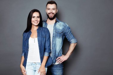 Güzel ve mutlu genç çift aşk veya aile eğleniyor ve birbirimizi dalga ve izole bir gri arka plan üzerinde poz rahat kıyafet içinde.