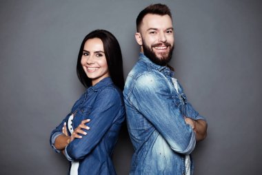 Güzel ve mutlu genç çift aşk veya aile eğleniyor ve birbirimizi dalga ve izole bir gri arka plan üzerinde poz rahat kıyafet içinde.