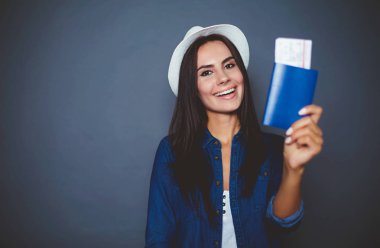 Kot gömlek gri bir arka plan üzerinde elinde bir pasaport ve hava bilet güzel modern genç kadınla izole.