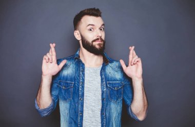 O-cekti iş eğer sadece. Yakışıklı delikanlı kot gömlek ile kenetlenmiş parmaklar karşı gri arka planı arıyorum. Bir dilek tut.