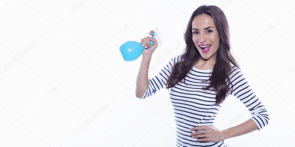 House cleaning. A cheerful beautiful and energetic young woman with a nebulizer in her hands is cleaning her apartment. Means to clean glass.