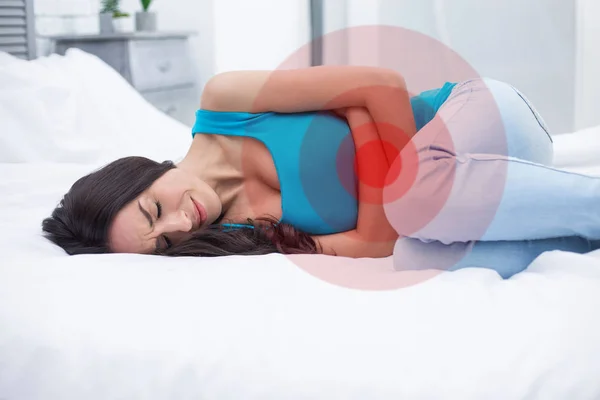 Kadın ağrı ya da adet sendromu. Evde bir yatakta yatarken genç bir kadın mide tutar ve spazmları ile bukleler.