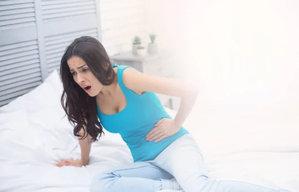 女性の痛みや月経症候群 自宅ベッドの上で横になっている若い女性彼女の胃の上に保持し カールのけいれん — ストック写真