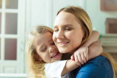 Anne seni seviyorum! Anne ve kızı birbirlerine gözleri evde kanepede kapalı ile çok sıkı sarılmak.