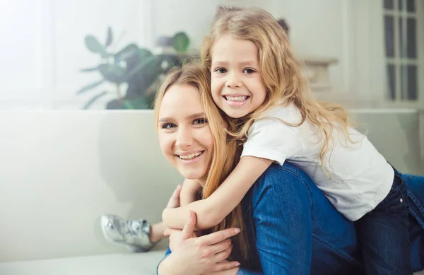 微笑着 快乐的妈妈和女儿在沙发上互相拥抱 妈妈和女儿玩得开心 — 图库照片