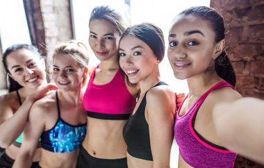 Kızlar gülümseyin! Genç kadın sporcular eğitimden sonra gülümseyen güzel çok etnik gruptan oluşan grup telefonda fotoğraflandı ya da selfie. Spordan sonra.