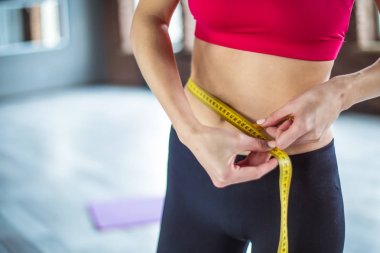 Atletik gülümseyen ince kadın beline egzersiz salonunda sonra ölçü bandı tarafından ölçme