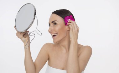 Temiz cilt ve çiçek beyaz arka plan üzerinde poz kafasına güzel genç gülümseyen kadın. Güzellik ve spa. Yüz ve vücut bakımı. Kadın sağlığı. Kozmetik.