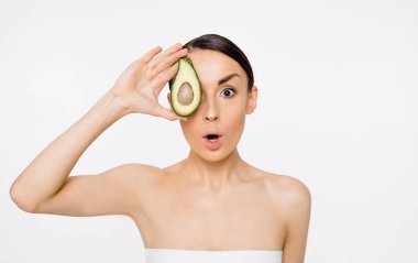 Sağlıklı bir vücut için avokado. Güzel bir genç kız onun el ve Puan yarım avokado kameraya sahiptir..