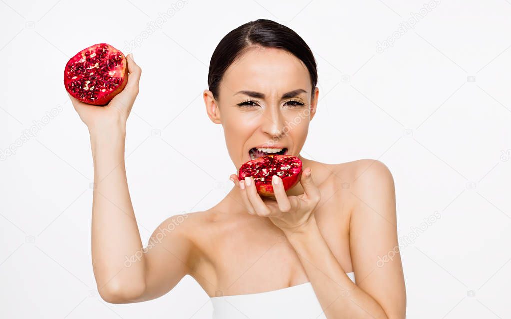 Happy and smiling beautiful woman with clean skin holding halves of pomegranate in their hands and having fun. Fruit health. Skin and body care.