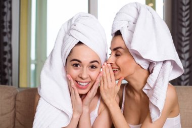 Bir spa sonra başlarına beyaz havlu güzel gülümseyen genç arkadaşlar dedikodu veya kanepede oturan bir şey tartışmak. Kızlar dinlenme.