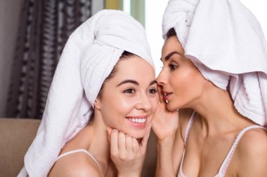 Bir spa sonra başlarına beyaz havlu güzel gülümseyen genç arkadaşlar dedikodu veya kanepede oturan bir şey tartışmak. Kızlar dinlenme.