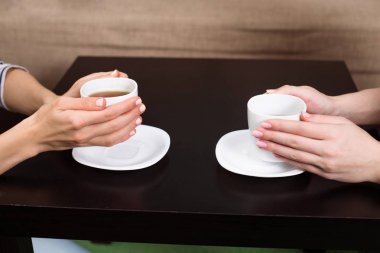 Eller yan görünüm fotoğrafı tutun beyaz fincan siyah kahve tablo evde veya Cafe.