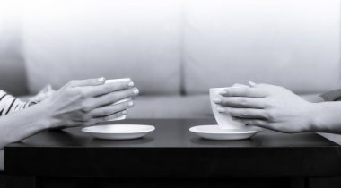 Eller yan görünüm fotoğrafı tutun beyaz fincan siyah kahve tablo evde veya Cafe.