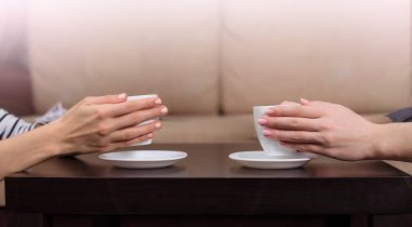 Eller yan görünüm fotoğrafı tutun beyaz fincan siyah kahve tablo evde veya Cafe.