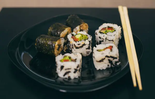 供应一盘日本料理 卷或寿司放在桌子上的黑色盘子里 — 图库照片