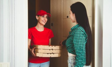 Daire ya da ev müşteriye pizza üç kutu kırmızı üniformalı genç gülümseyen kız kurye teslim.