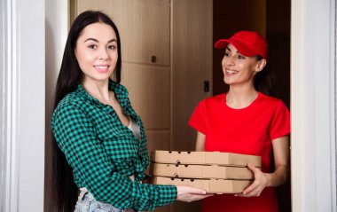Daire ya da ev müşteriye pizza üç kutu kırmızı üniformalı genç gülümseyen kız kurye teslim.