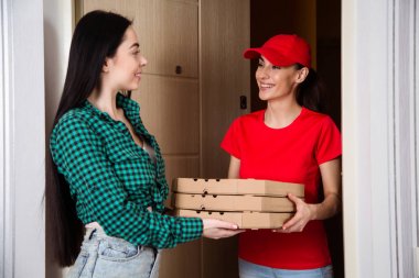 Daire ya da ev müşteriye pizza üç kutu kırmızı üniformalı genç gülümseyen kız kurye teslim.