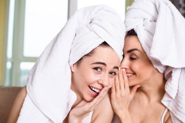 Bir spa sonra başlarına beyaz havlu güzel gülümseyen genç arkadaşlar dedikodu veya kanepede oturan bir şey tartışmak. Kızlar dinlenme.