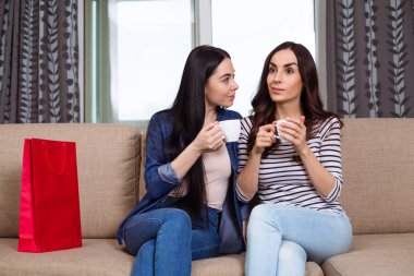 İki güzel kadın gülümseyerek evde kahve veya çay içmek ve haberleri tartışmak