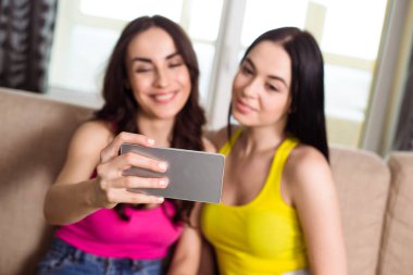 Arkadaşlarım Selfie fotoğraf. İki güzel kız fotoğrafları akıllı evde kanepede yapıyor serin