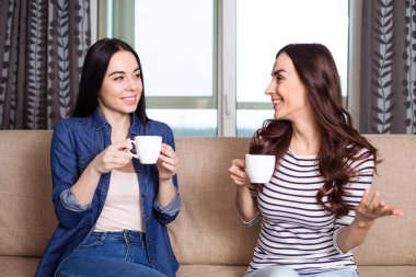 Genç güzellik kızlar evde çay bardak ile konuşmak.