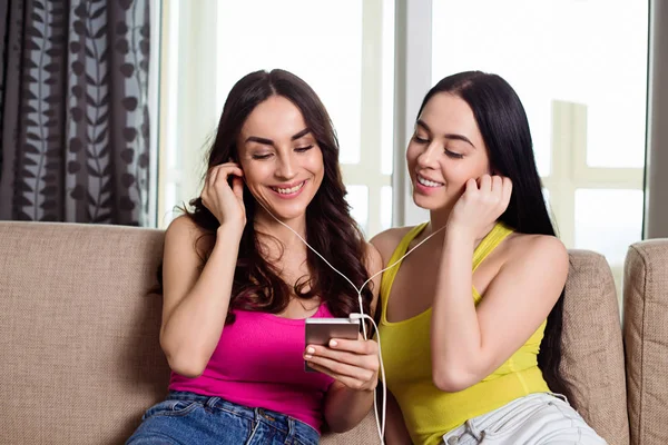 Закройте Фотографию Двух Улыбающихся Молодых Женщин Наушниками Слушающих Музыку Мобильного — стоковое фото