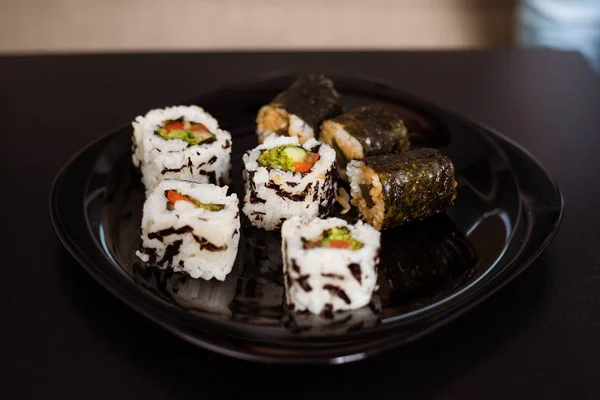 供应一盘日本料理 卷或寿司放在桌子上的黑色盘子里 — 图库照片