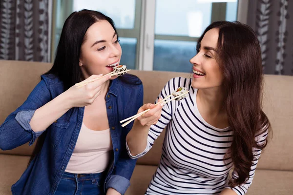 Beautiful happy women eat many vegan rolls at home
