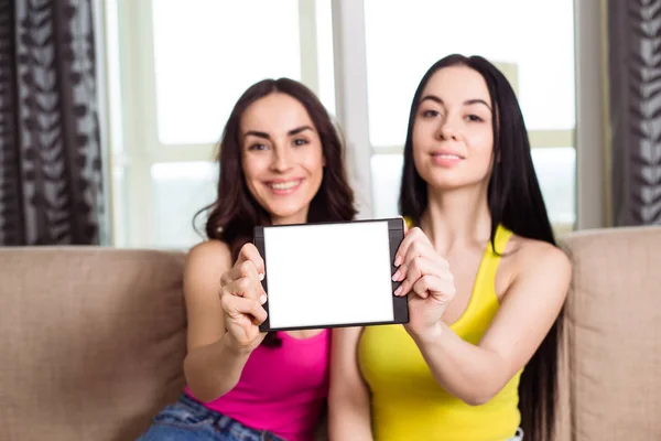 Két Mosolygó Gyönyörű Modern Lány Meg Kanapén Egy Fehér Tabletta — Stock Fotó