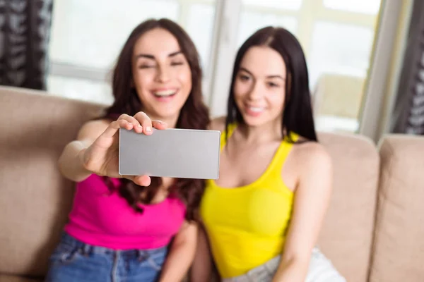 親友の Selfie つのクールな美しい姉妹の自宅をスマート フォン ソファの上で写真をやって — ストック写真