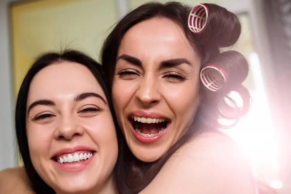 Красивые Улыбающиеся Юные Сестры Готовятся Вечеринке Делают Прически Сидя Диване — стоковое фото