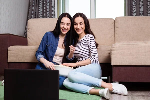 つの若いガール フレンドやポップコーンが付いているソファで自宅のテレビ映画を見てカジュアルな服装で姉妹 — ストック写真
