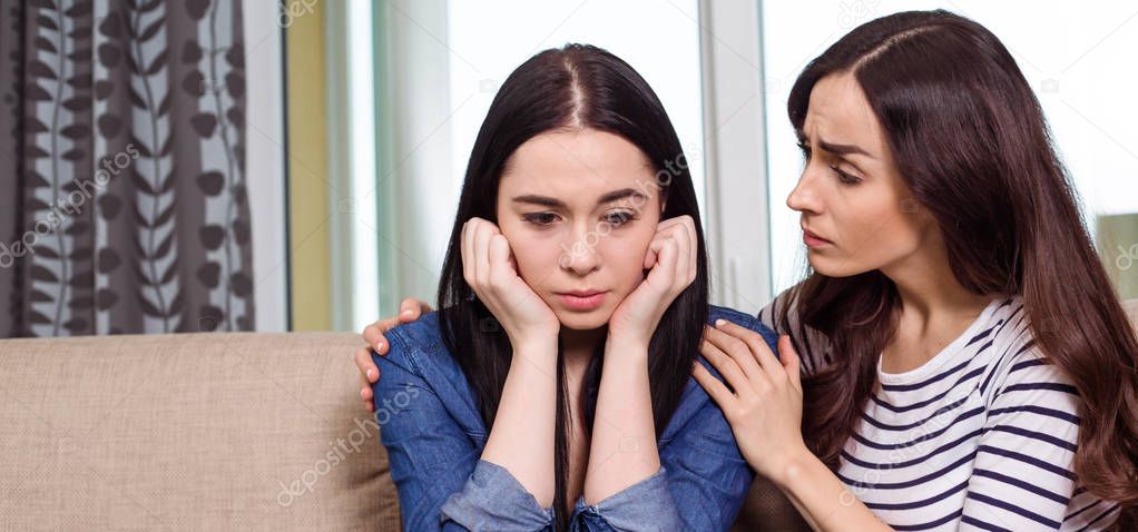 Young Girl calms down another one who are crying at home on the couch