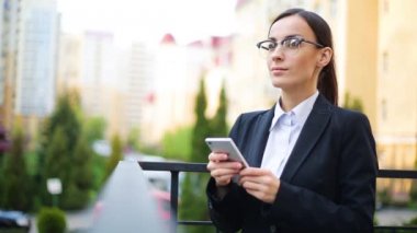 Gözlük güneşli kent sokakları ve sohbet istemci, neşeli kız açık havada cep telefonu kullanarak, gün batımı arka plan ile çekici genç iş kadını