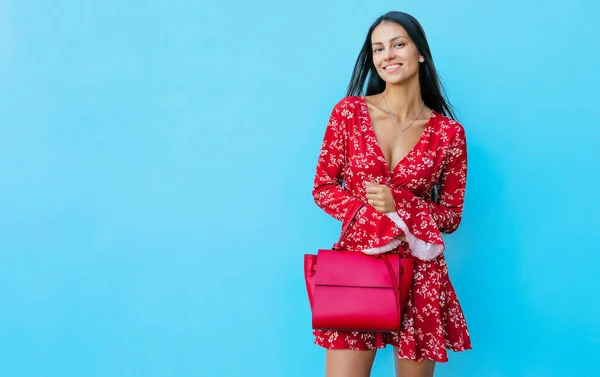 Gülümseyen Kırmızı Elbiseli Mutlu Bir Kadın Mavi Arka Planda Çantasını — Stok fotoğraf