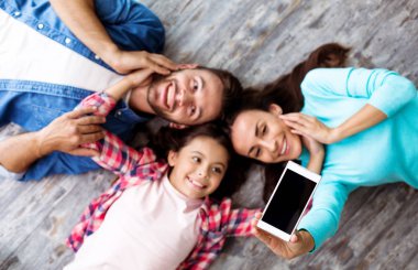 Üç kişilik mutlu bir aile yerde yatıyor. 