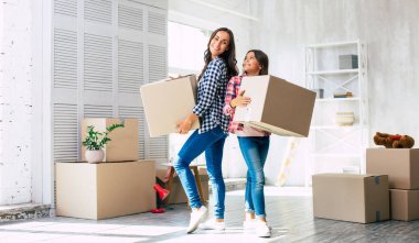 Yardım etmeme izin ver! Küçük çocuk gülümserken güzel annesine yeni evlerinde karton kutularla yardım ediyor..